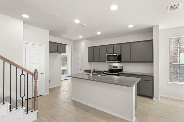 a kitchen with stainless steel appliances granite countertop a stove a sink and a refrigerator