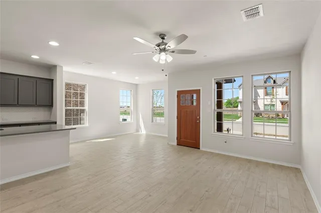 a view of an empty room with a window and kitchen view