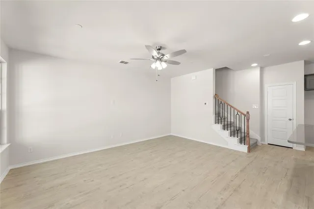a view of an empty room with a window and kitchen view