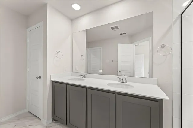 a bathroom with a double vanity sink mirror and shower