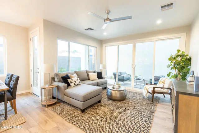 a living room with furniture a large window and a dining table with wooden floor