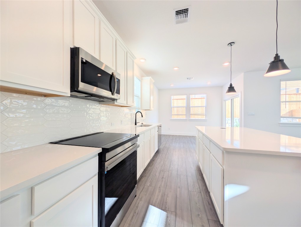 113 Sycamore Pnes Lane Kyle, TX 78640 - Photo 8 of 32 a kitchen with stainless steel appliances a sink a stove a microwave and white cabinets