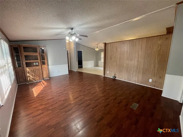 an empty room with wooden floor fireplace and windows