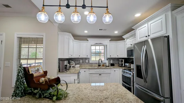 a kitchen with stainless steel appliances granite countertop a refrigerator a stove a sink dishwasher a refrigerator white cabinets and wooden floor