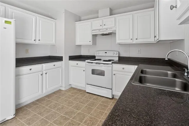 a kitchen with granite countertop white cabinets and white appliances