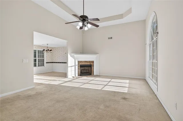 an empty room with chandelier fan and windows