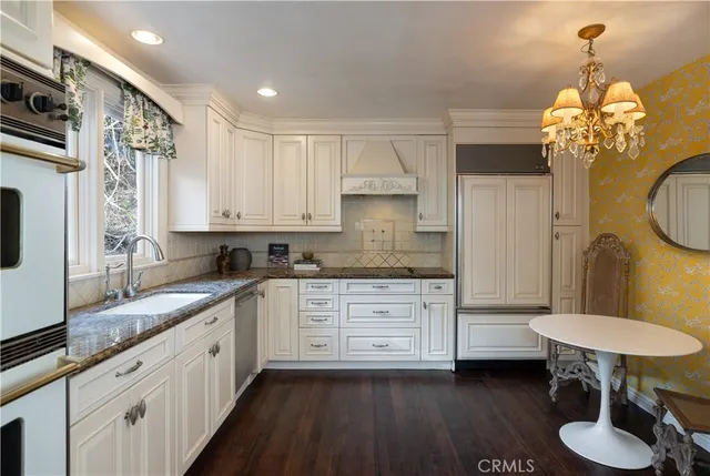 a kitchen with stainless steel appliances granite countertop a sink a stove cabinets dining table and chairs