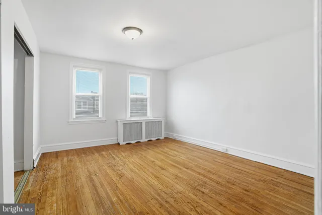 an empty room with wooden floor closet and windows