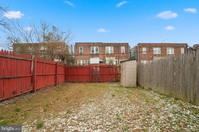 a backyard of a house with large trees and wooden fence
