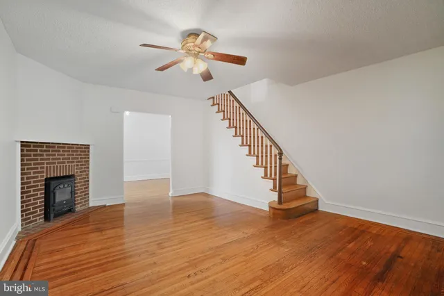 a view of an empty room with wooden floor and a fireplace