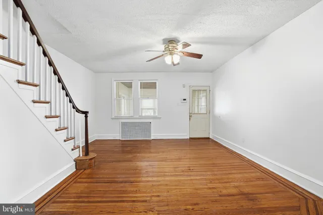 a view of an empty room with wooden floor and stairs