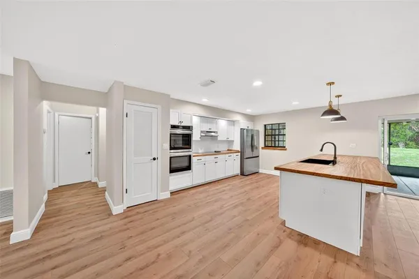 a kitchen with stainless steel appliances white cabinets a stove a microwave and a refrigerator