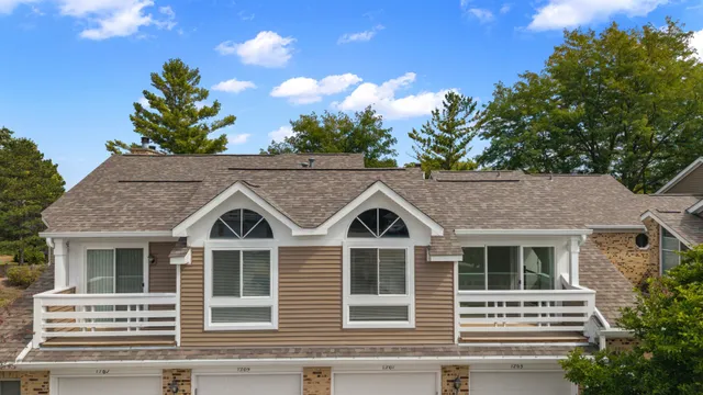 a view of a white house with large windows and a small yard