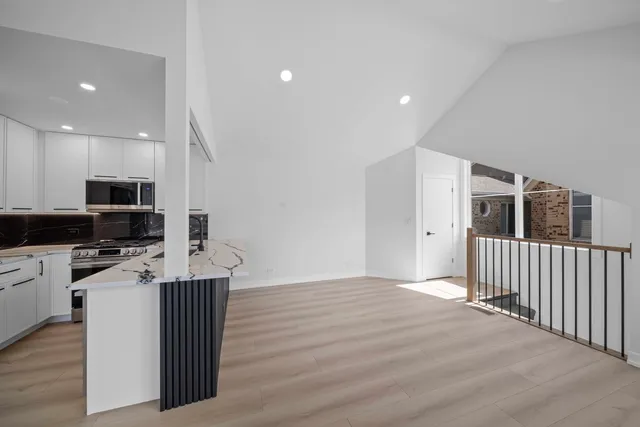 a kitchen with stainless steel appliances wooden floor and view living room