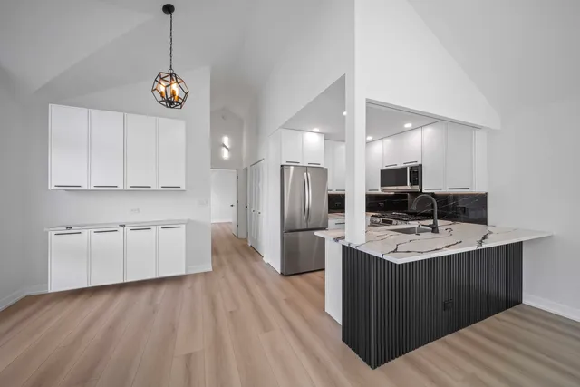 a kitchen with stainless steel appliances granite countertop a sink dishwasher a refrigerator and a stove with wooden floor