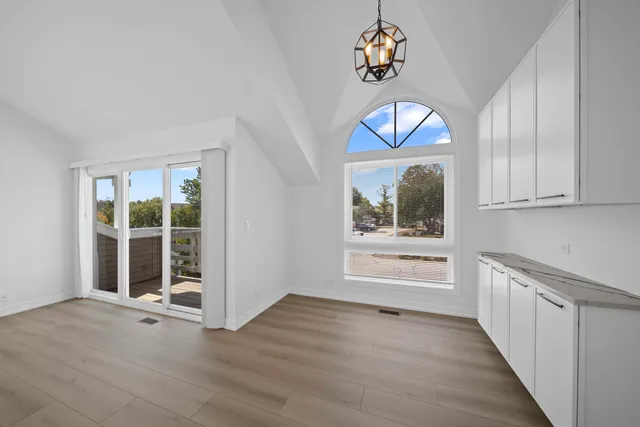 an empty room with wooden floor cabinet and windows