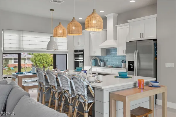 a kitchen with stainless steel appliances kitchen island granite countertop a table chairs and a refrigerator