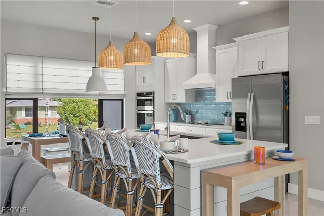 a kitchen with stainless steel appliances kitchen island granite countertop a table chairs and a refrigerator