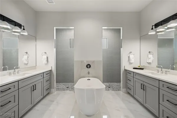 a spacious bathroom with a double vanity sink a large mirror and a bathtub