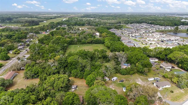 an aerial view of residential houses with outdoor space and trees