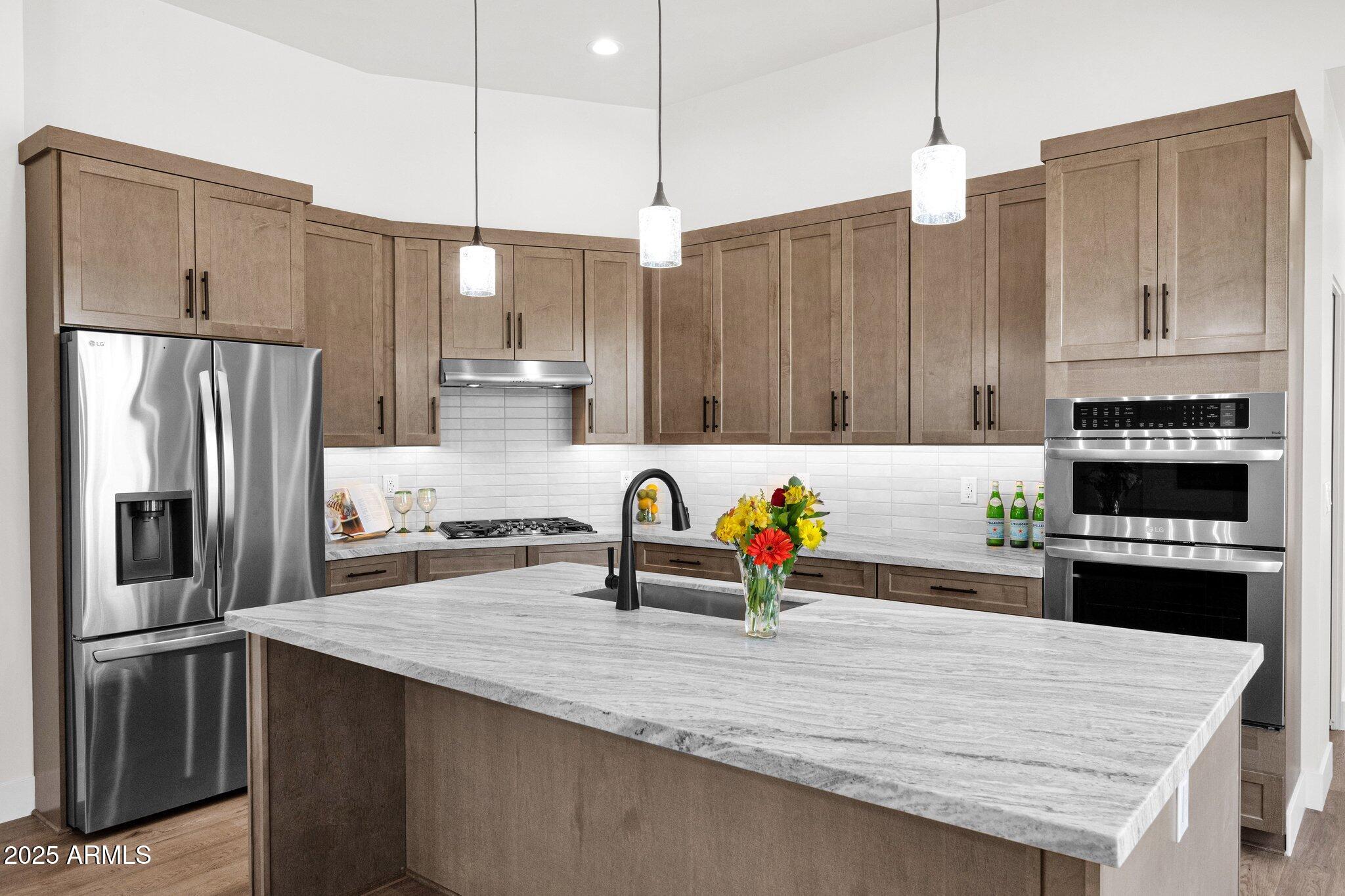 553 West Cavalry Road New River, AZ 85087 - Photo 6 of 26 a kitchen with stainless steel appliances granite countertop a refrigerator a stove and a sink with wooden floor