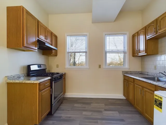 a kitchen with a refrigerator a stove top oven a sink and a window