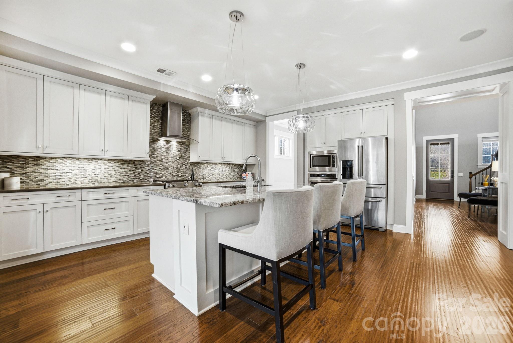 17413 Robbins Ridge Road Cornelius, NC 28031 - Photo 12 of 48 a kitchen with stainless steel appliances granite countertop a stove top oven a sink dishwasher a dining table and chairs with wooden floor