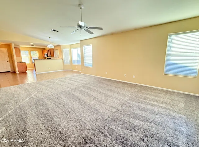 an empty room with a window and chandelier fan