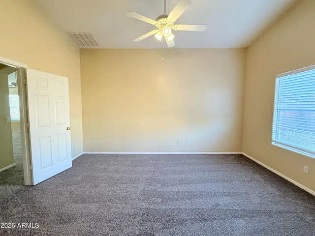 an empty room with a ceiling fan and carpet