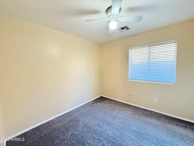 an empty room with a ceiling fan and a window