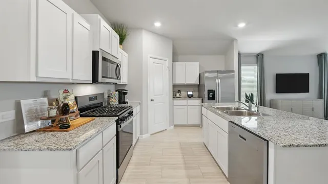 a kitchen with kitchen island granite countertop a sink cabinets and stainless steel appliances