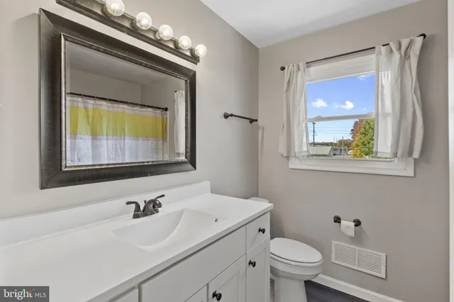 a bathroom with a toilet a sink and mirror