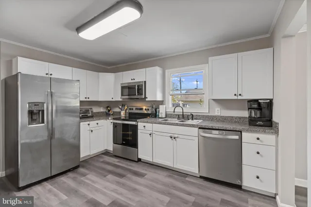 a kitchen with white cabinets stainless steel appliances and a window