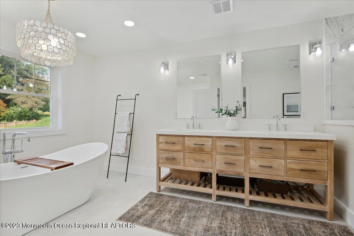 17 Quaker Road Middletown, NJ 07748 - Photo 32 of 65 a bathroom with a double vanity sink a mirror and a bathtub