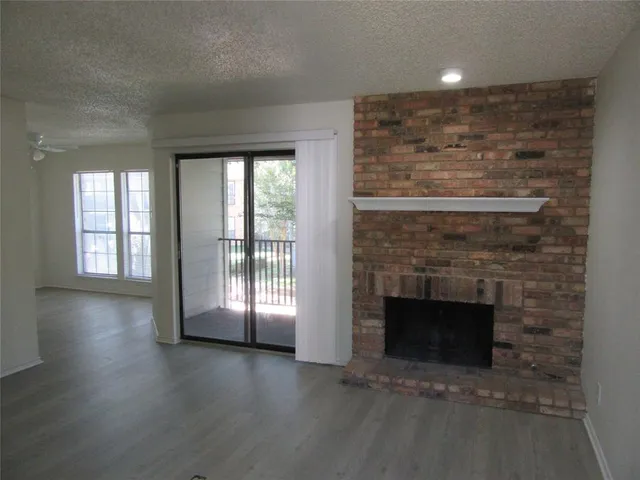 an empty room with wooden floor fireplace and windows