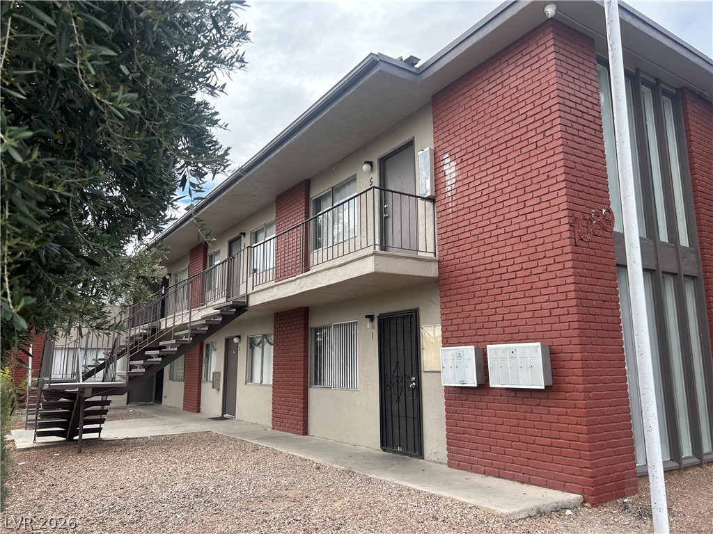 1089 East Desert Inn Road, Unit 3 Las Vegas, NV 89109 - Photo 15 of 15 Two-story brick and stucco apartment building with external metal staircases and mailboxes.