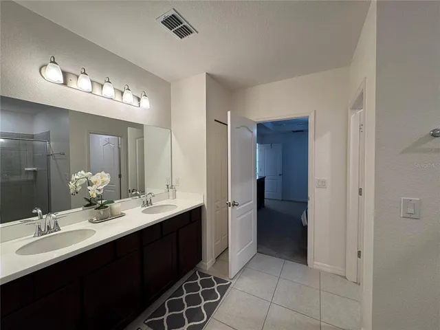 a bathroom with a double vanity sink a mirror and a shower