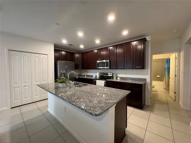 a kitchen with stainless steel appliances granite countertop a stove top oven a sink and a refrigerator