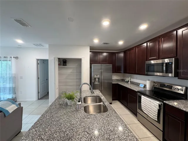 a kitchen with stainless steel appliances granite countertop a sink stove and refrigerator