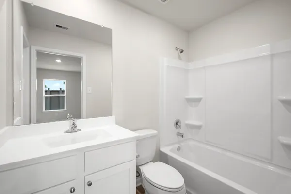 a bathroom with a bathtub shower sink vanity mirror and toilet