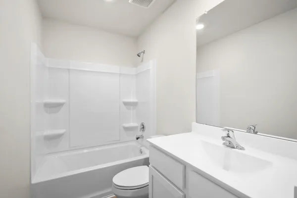 a bathroom with a bathtub shower sink vanity mirror and toilet