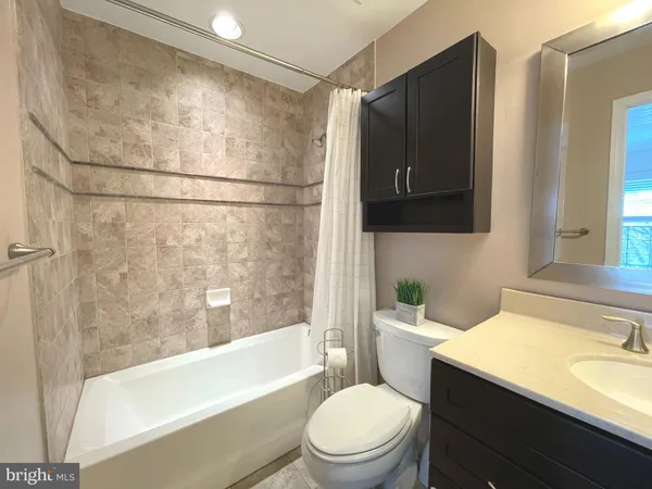 a bathroom with a granite countertop bathtub shower sink mirror and toilet