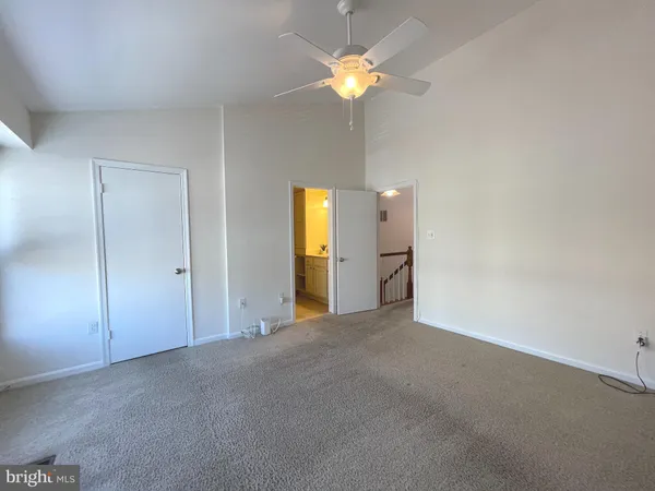 a view of an empty room with a chandelier fan