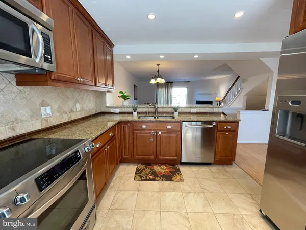 a large kitchen with stainless steel appliances granite countertop a stove a sink dishwasher and a microwave