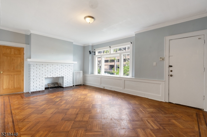 148 Lyons Avenue, Unit 1 Newark, NJ 07112 - Photo 2 of 9 an empty room with windows and fireplace
