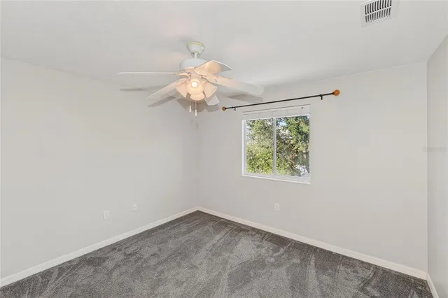 an empty room with closet and a ceiling fan