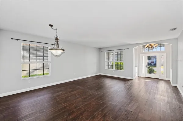an empty room with wooden floor cabinet and windows