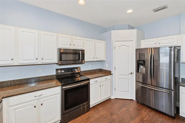 a kitchen with a refrigerator stove and white cabinets