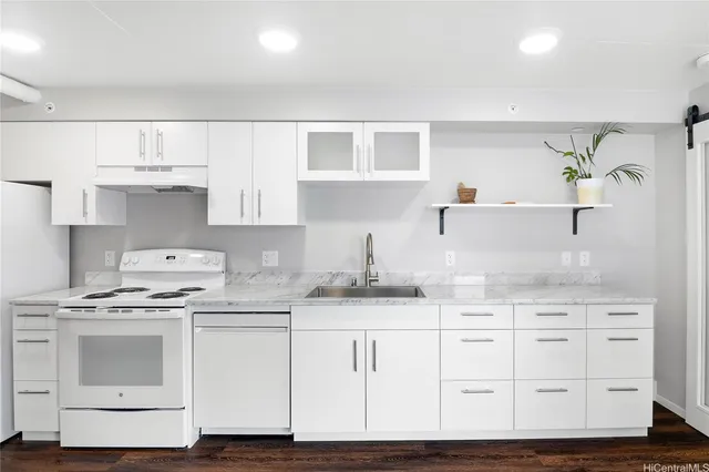 a kitchen with granite countertop a white stove top oven and cabinets
