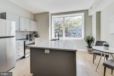 a kitchen with stainless steel appliances a sink a table and chairs in it